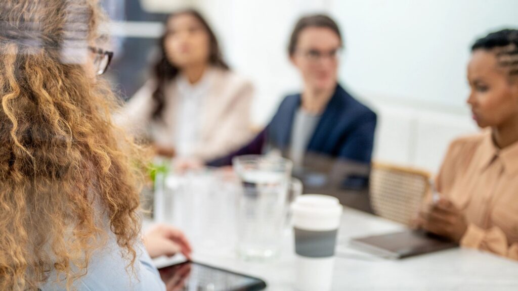 Businesswomen brainstorming in morning briefing, selective focus